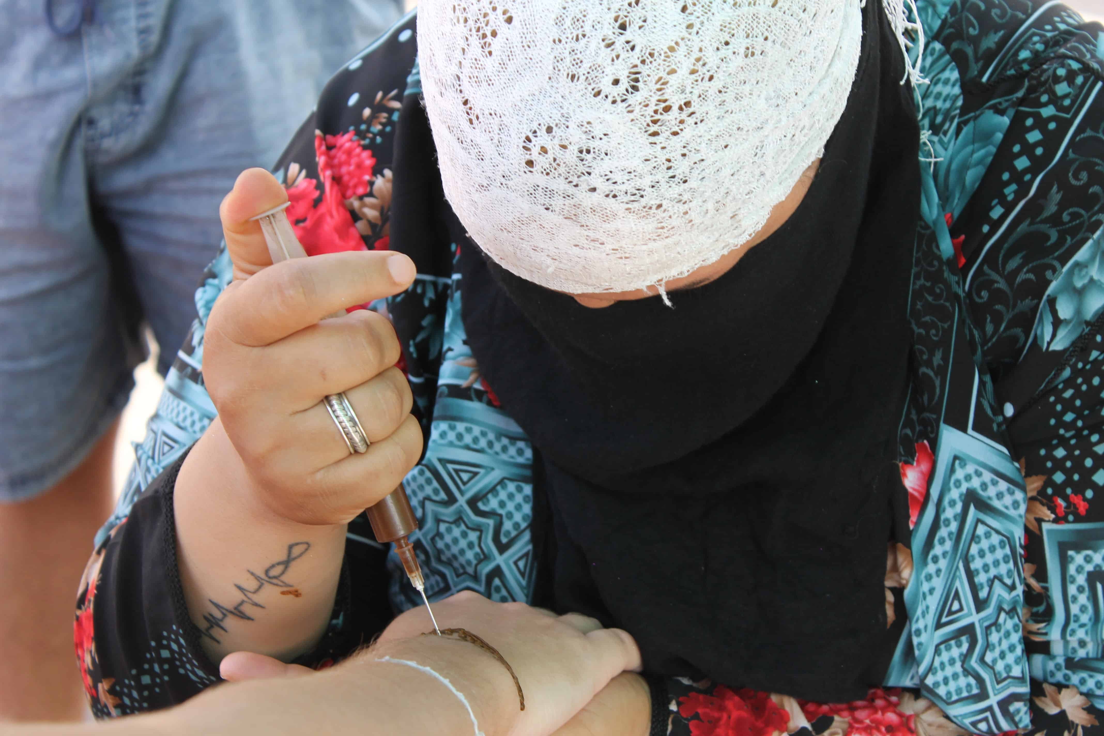 tatuaje de henna mujer haciendo un tatuaje de henna en la plaza Jamaa el Fna